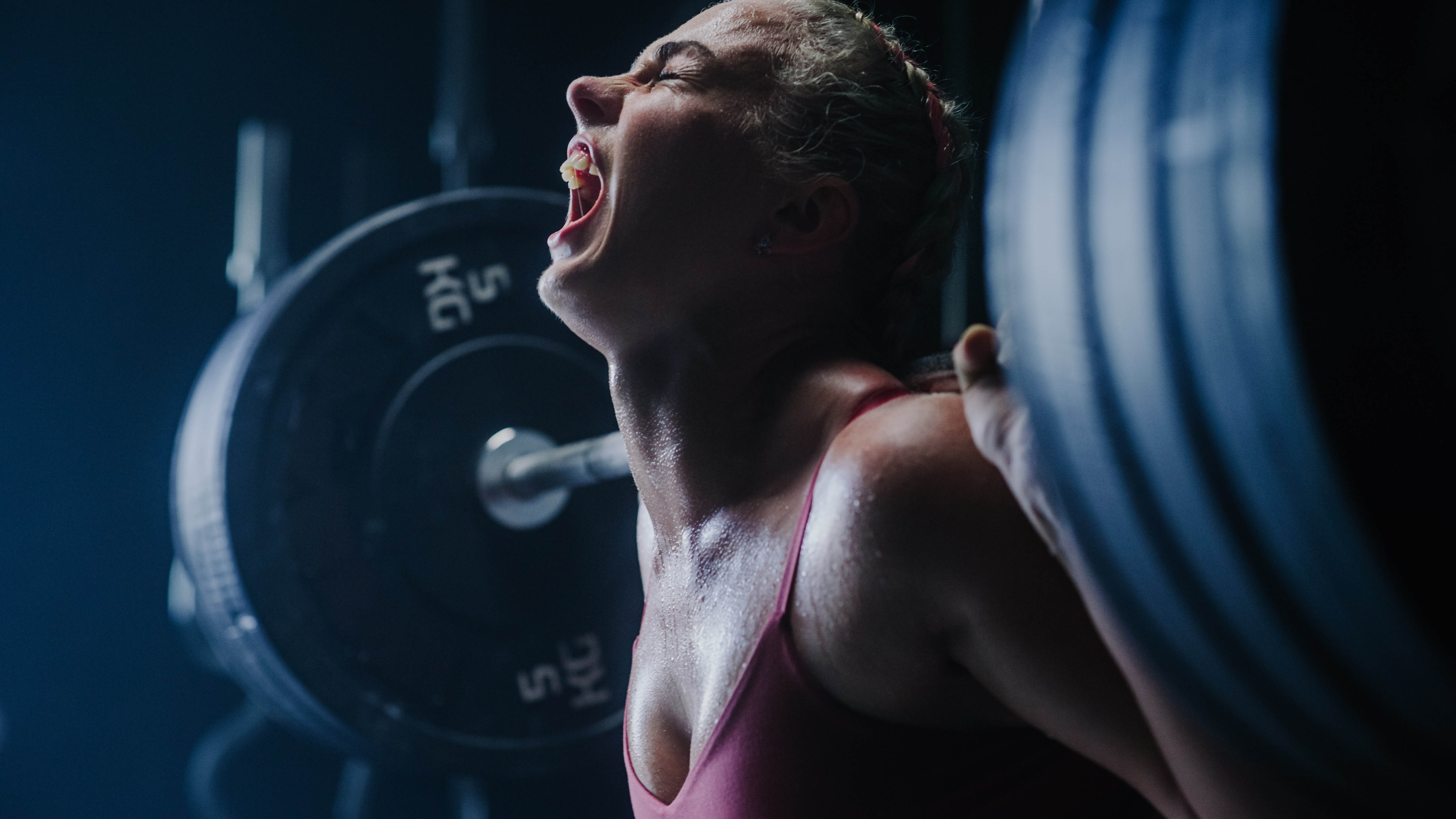 Young woman doing a deadlift with her head tilted back and yelling to the gym ceiling Young woman doing a deadlift with her head tilted back and yelling to the gym ceiling